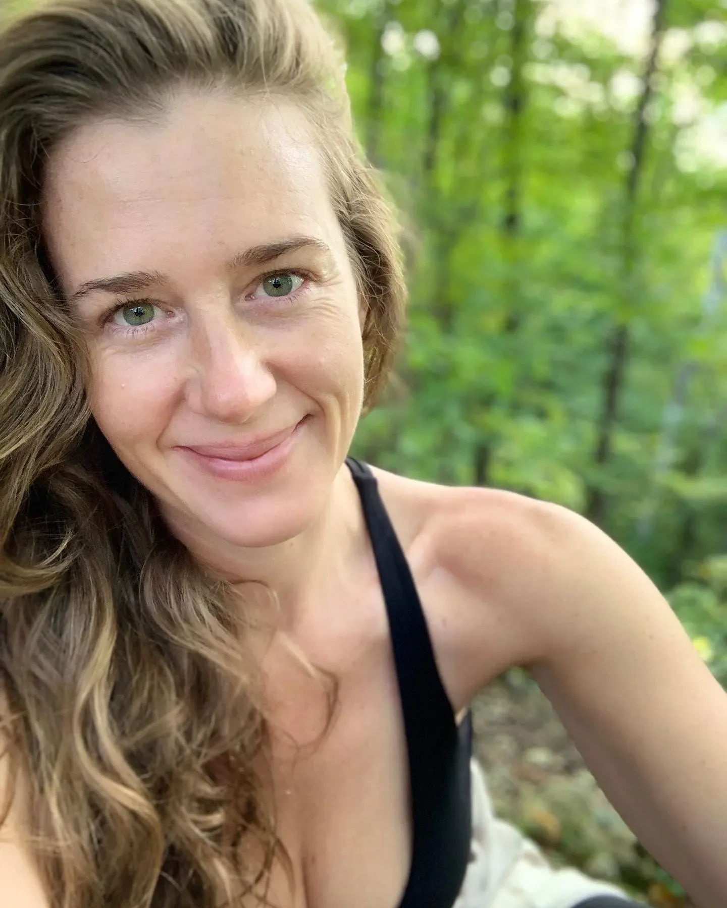 Katie Hamilton smiling, outdoors in summer woodland