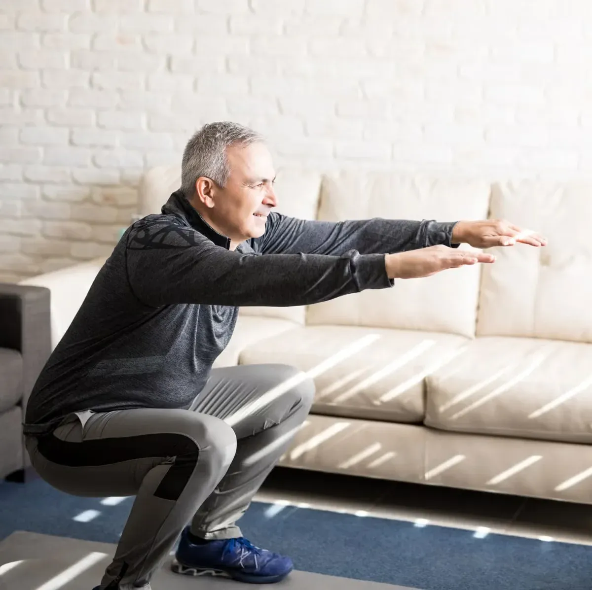 A bodyweight squat being performed at home in a bright living room